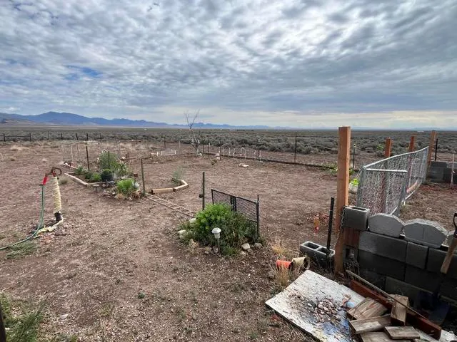 Expansive outdoor space featuring a garden area with raised beds, partial fencing, and distant mountain scenery
