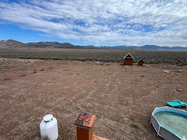 Expansive open landscape featuring distant mountains and two small structures