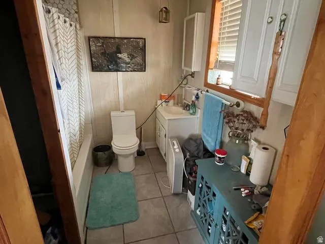 Compact bathroom featuring a white toilet, integrated bathtub and shower, and a single vanity with a white basin