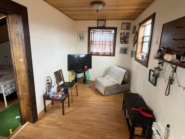Wood-finish flooring with a complementary ceiling, two windows with wood trim, and a wall-mounted light fixture
