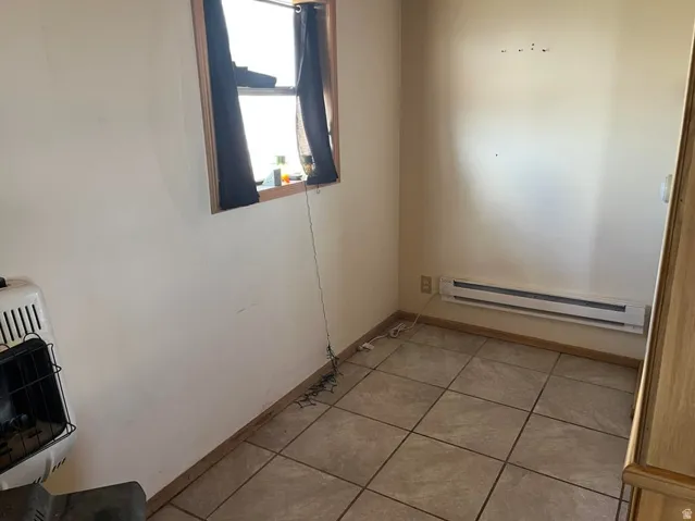 Tiled flooring, natural light through a window with wood trim, and baseboard heating