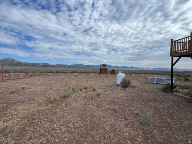 Expansive rural property featuring an elevated wood-finish deck, propane tank, and distant mountain scenery