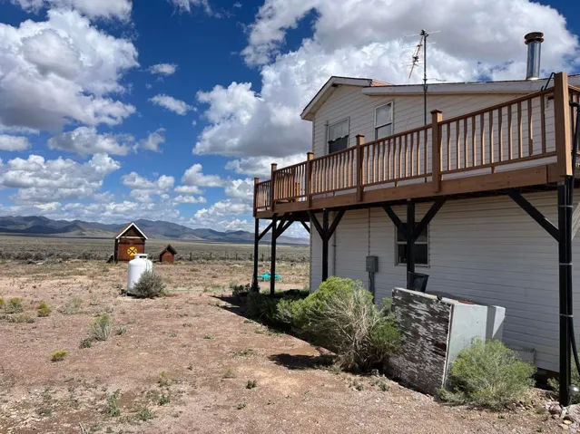 Exterior balcony with wood railing, white siding, and metal chimney