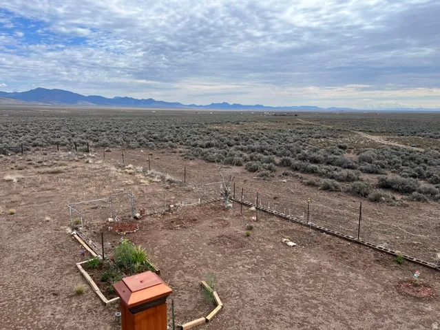 Expansive outdoor area featuring a distant mountain range, natural vegetation, and a partially fenced perimeter