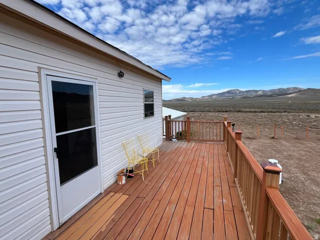 Expansive wooden deck with coordinating railings, white vinyl siding, and a white storm door