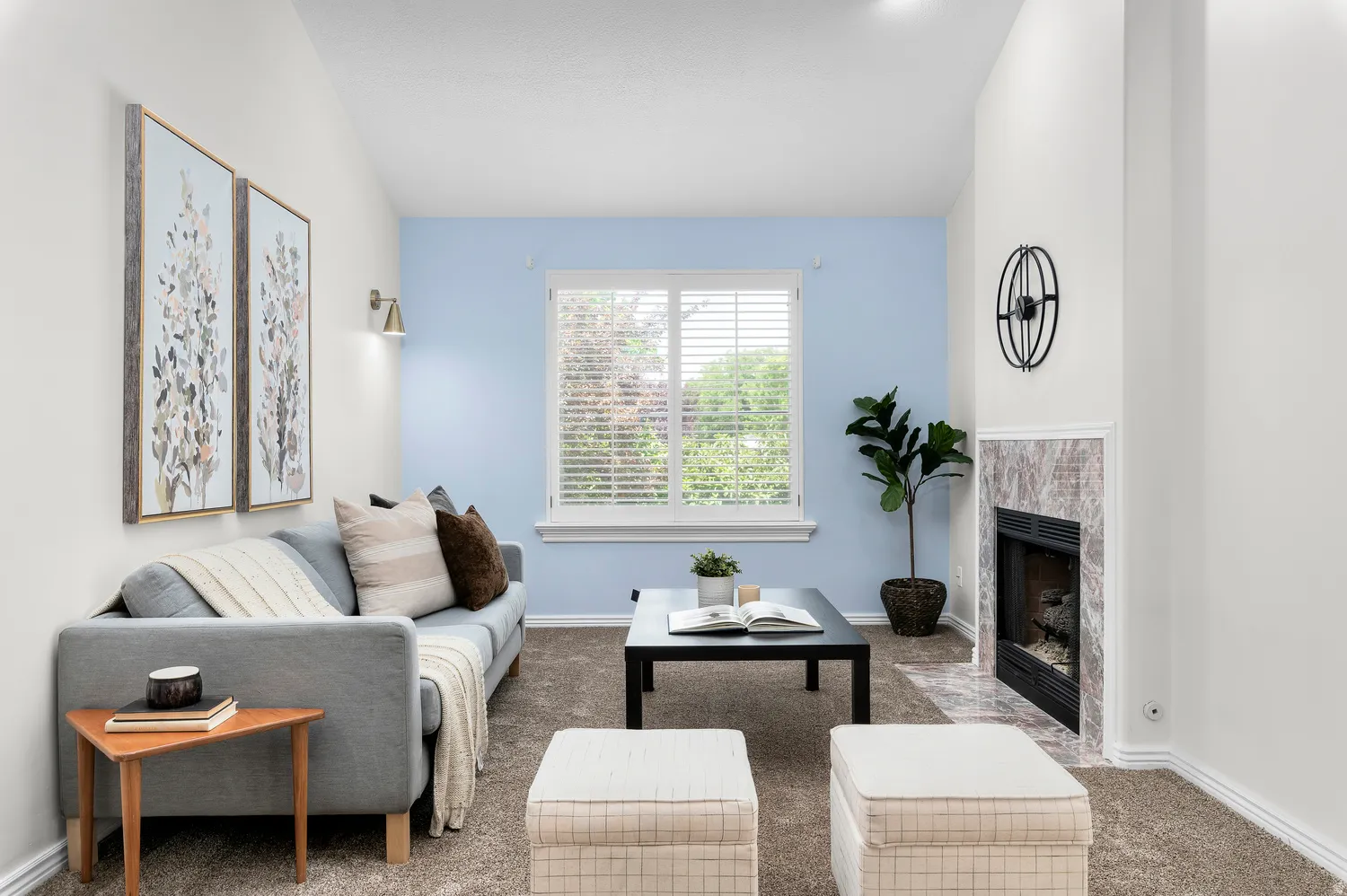 Carpeted room featuring a fireplace with a light-toned, veined stone surround, a window with horizontal blinds, and a built-in wall sconce