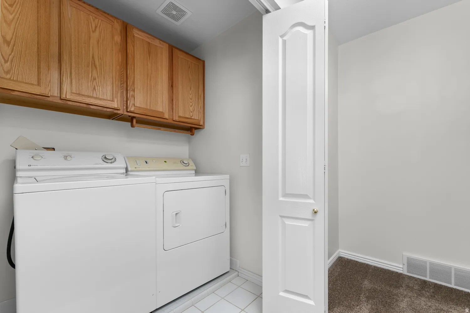 Utility area featuring overhead wood cabinetry and tile flooring