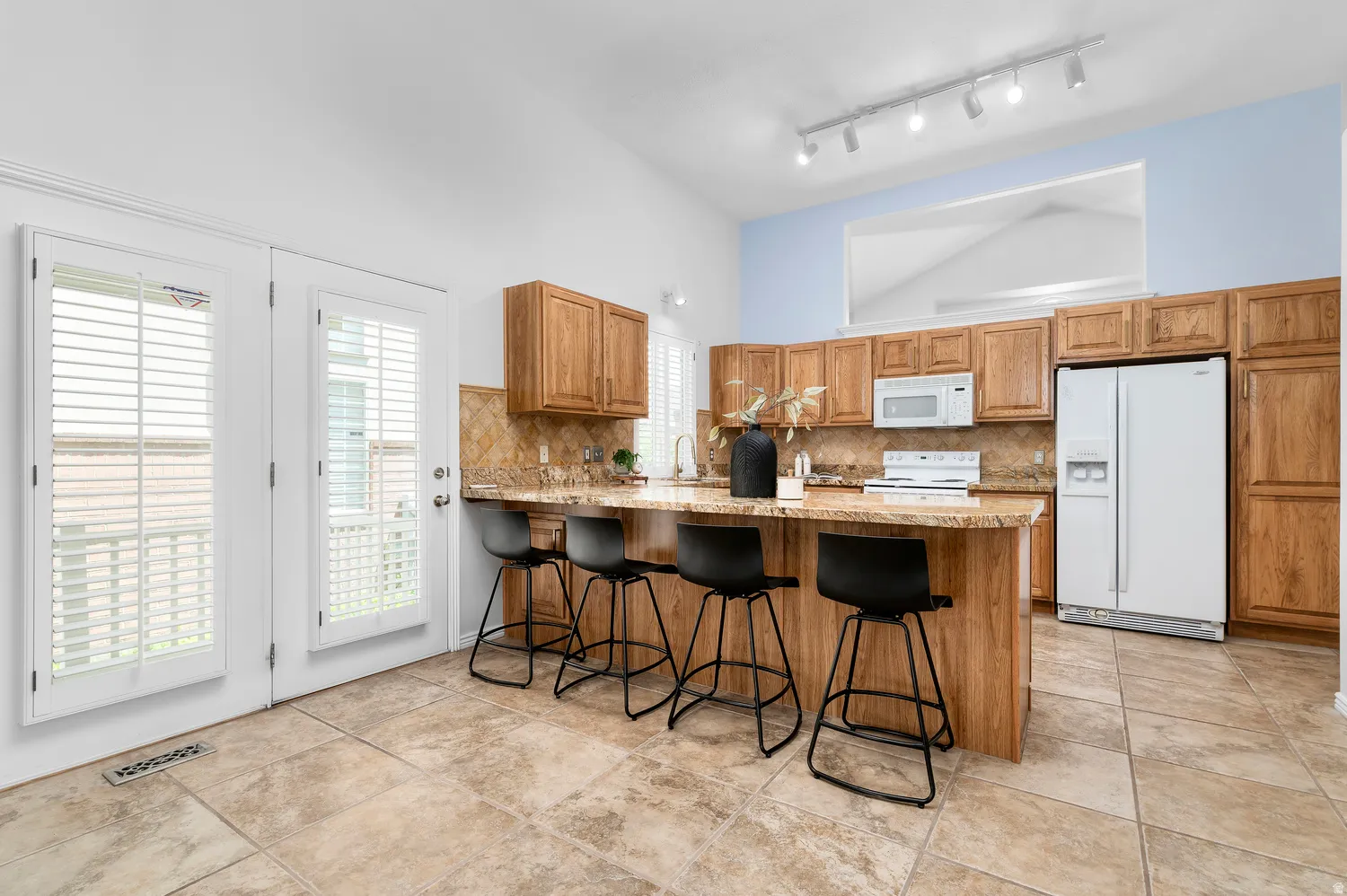 Kitchen featuring a vaulted ceiling and an expansive island with a granite countertop