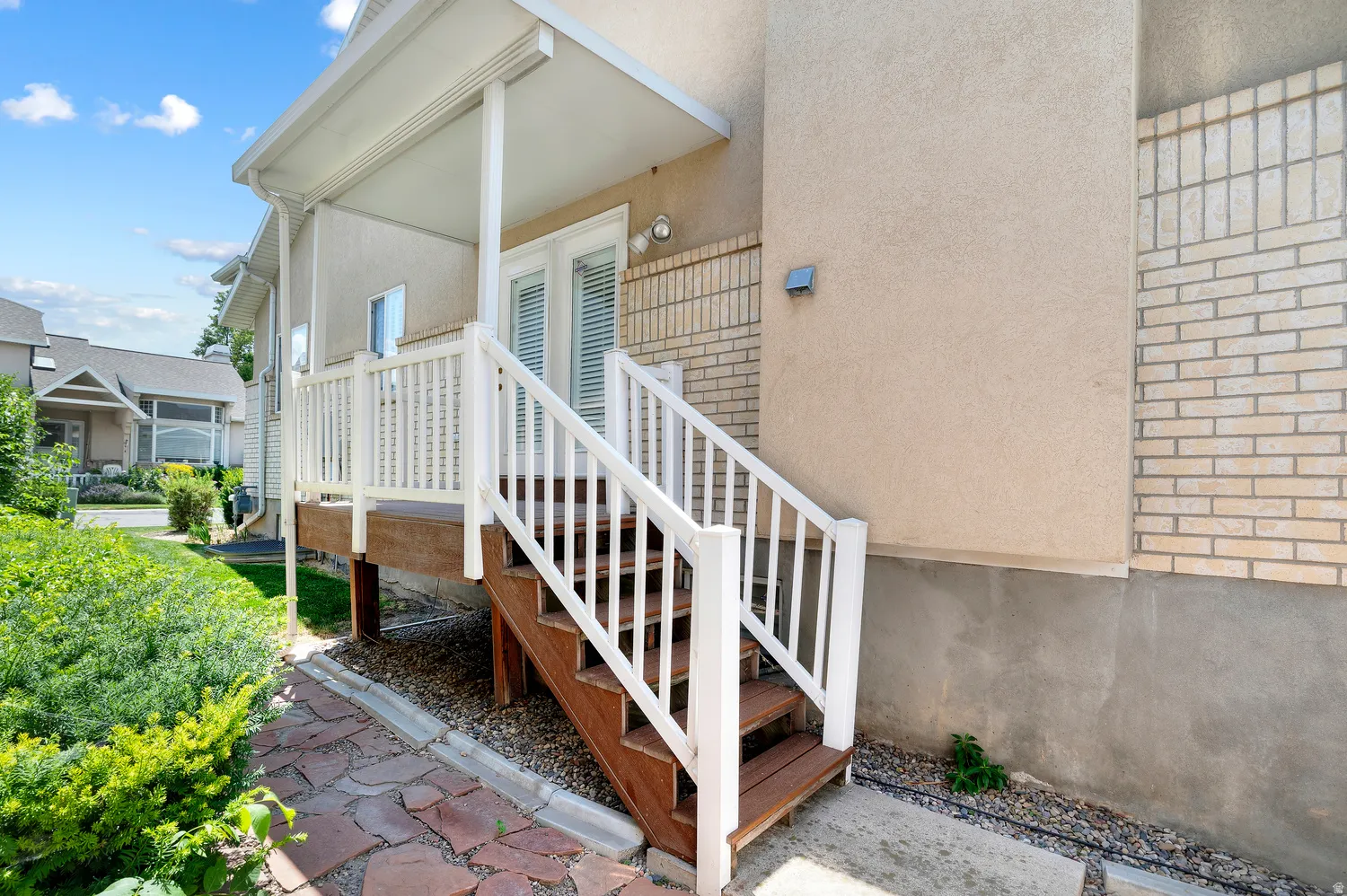 Covered porch with white railings and wood-finish steps