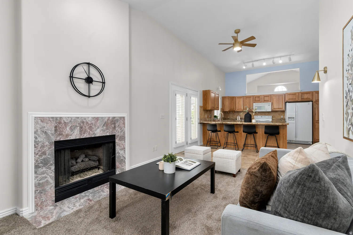 Living area featuring a fireplace with a stone surround, vaulted ceilings, and wood-finish flooring