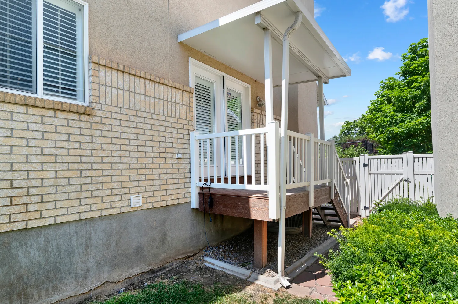 Covered deck featuring white railing, composite decking, and exterior wall-mounted lighting