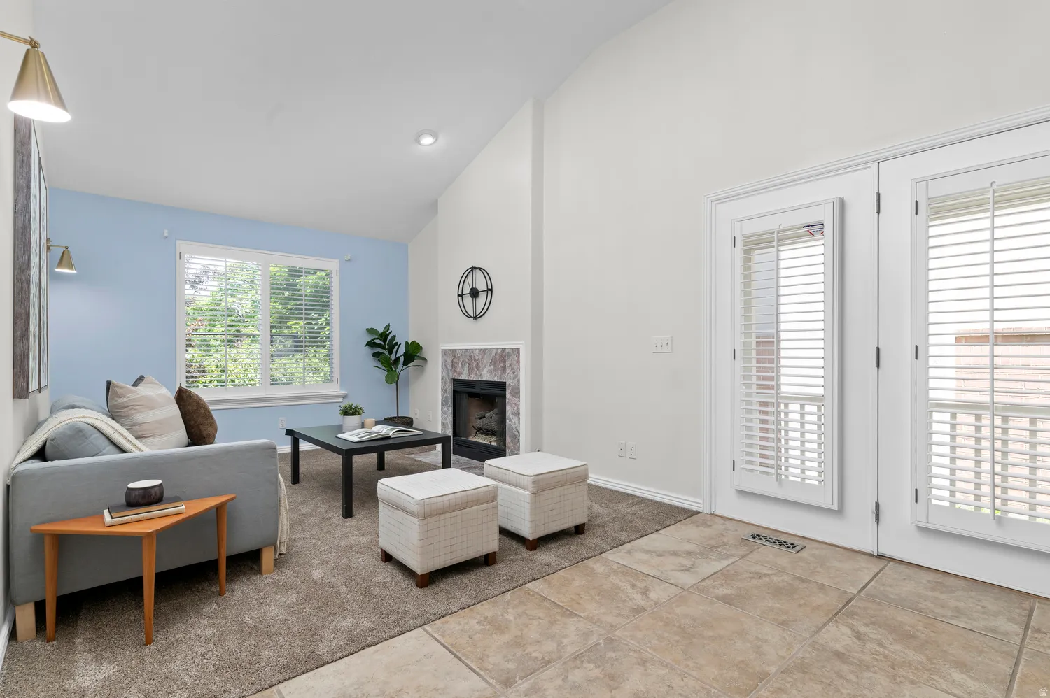 Living area featuring a fireplace with a stone surround, vaulted ceilings, and a light blue accent wall