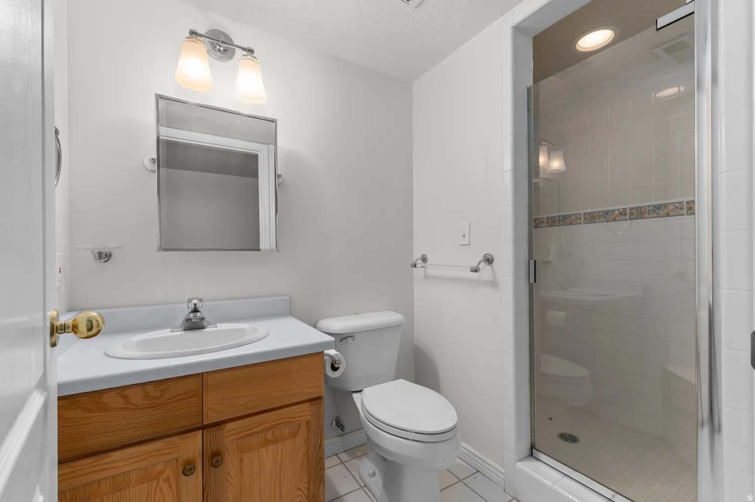 Bathroom featuring a glass-enclosed shower, a vanity with wood-finish cabinetry, a white countertop, and a chrome faucet