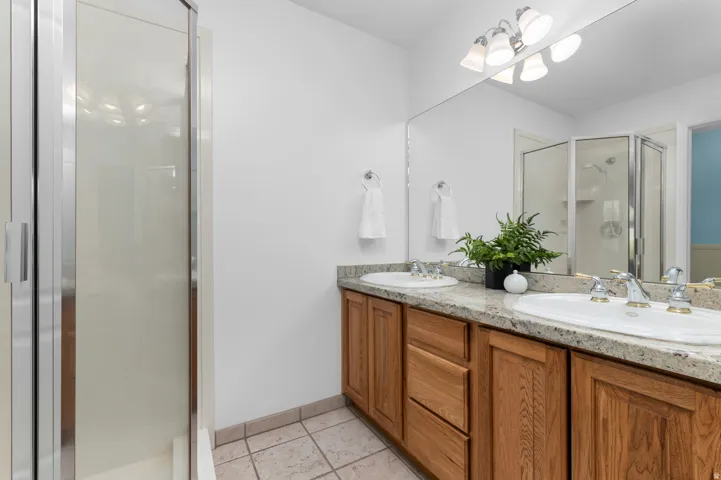 Primary Bathroom featuring a double vanity with granite countertop