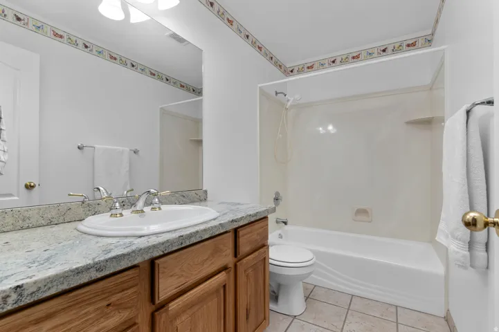 Bathroom featuring a vanity with a white oval sink, polished chrome faucet with brass accents, and a light-toned granite countertop