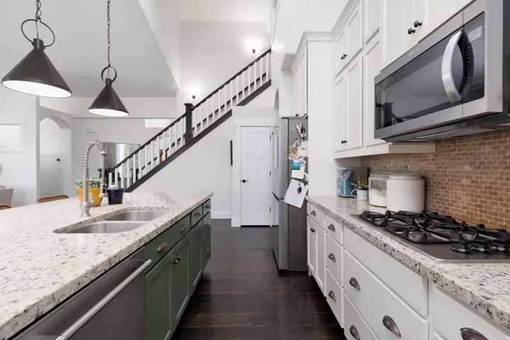 Kitchen featuring granite countertops, a gas cooktop, stainless steel microwave, and dark wood-finish flooring