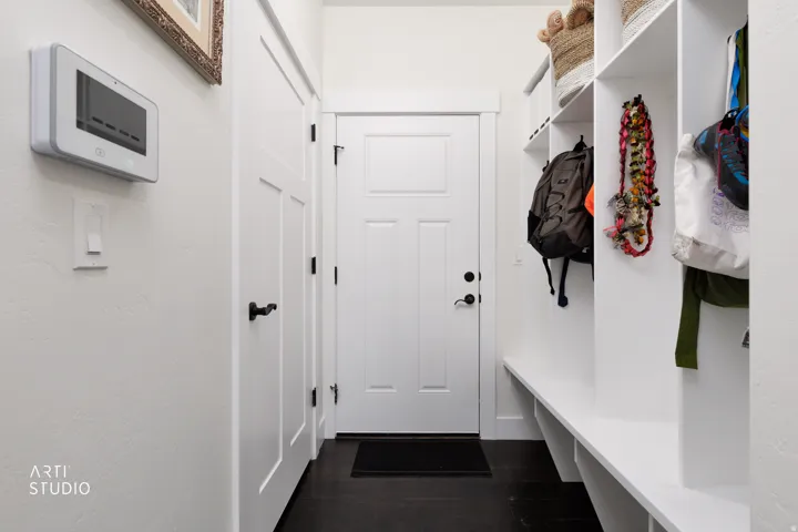 Entryway featuring a built-in white storage bench with open shelving, dark wood-finish flooring, and crisp white trim