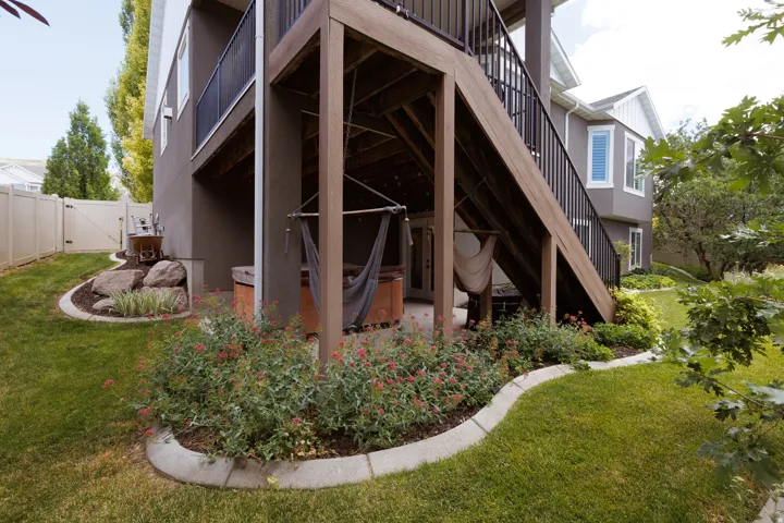 Multi-level outdoor living space featuring a ground-level patio, a wooden upper deck with dark railings, and a built-in spa