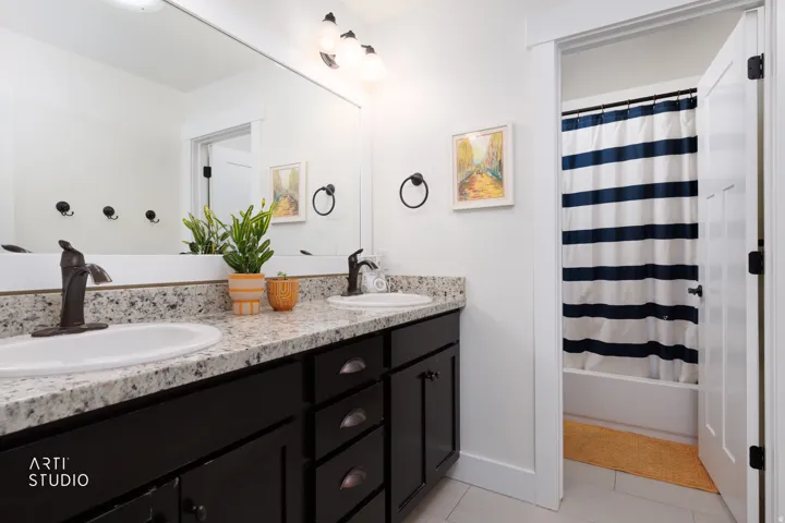 Double vanity featuring granite-style countertops, integrated oval sinks, and dark bronze-finish fixtures