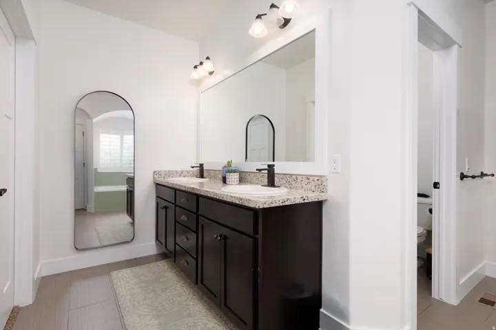 Bathroom featuring a dual vanity with dark wood cabinetry, granite-style countertops, and undermount sinks