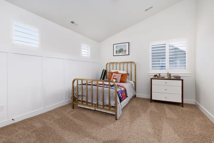 White paneled accent wall, vaulted ceiling, and carpeted flooring