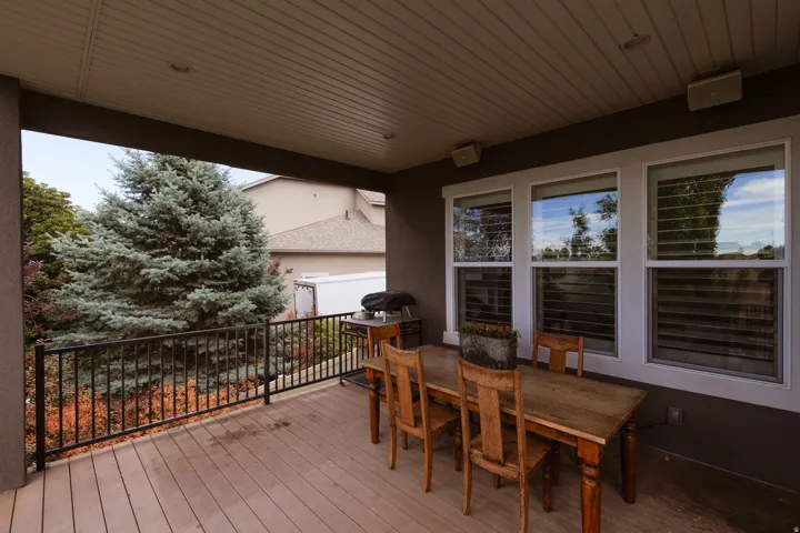 Covered outdoor deck featuring wood-finish flooring and a black metal railing