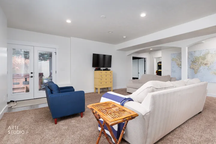 Spacious living area featuring neutral carpeting, white walls, and recessed lighting