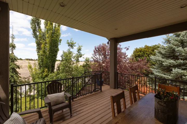 Covered outdoor deck featuring composite decking, black metal railings, and integrated overhead lighting