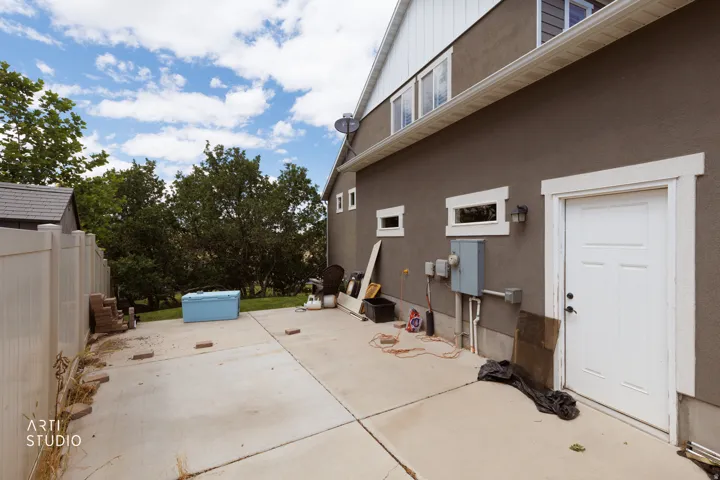 Exterior featuring a stucco finish with white trim, a white utility door, and multiple windows