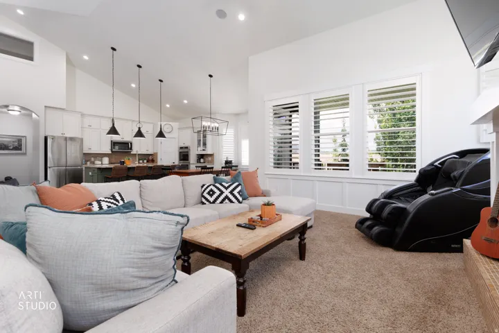 Open-concept living space featuring vaulted ceilings, recessed lighting, and large windows with plantation shutters