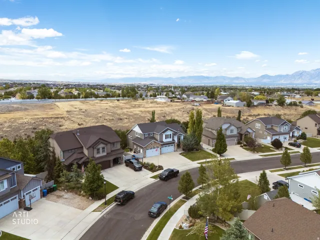 Residential street featuring a mix of two-story homes with varied architectural styles, attached garages, and landscaped front yards
