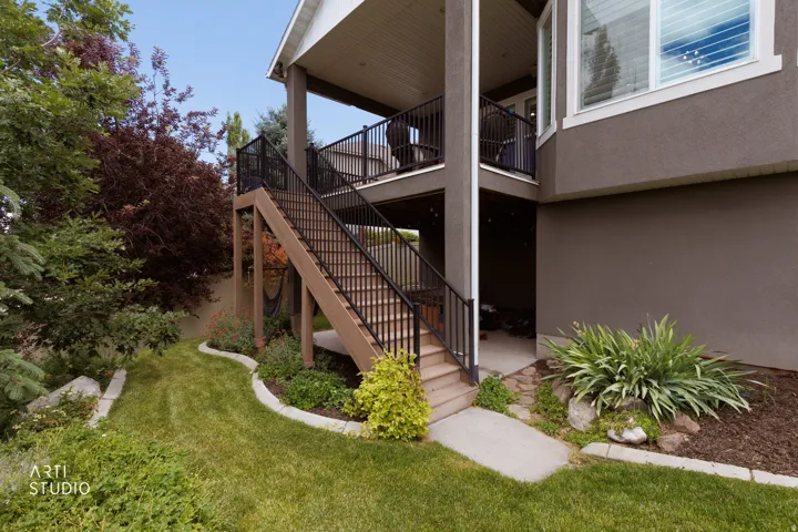 Exterior featuring a multi-level deck system with dark railings, a ground-level patio, and landscaping