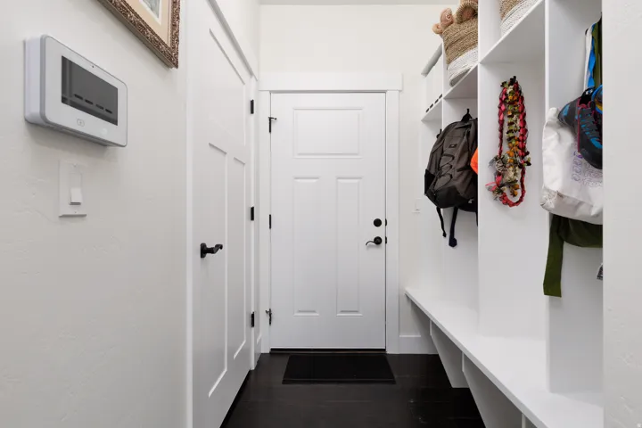 Entryway featuring built-in white cabinetry with open shelving and bench seating