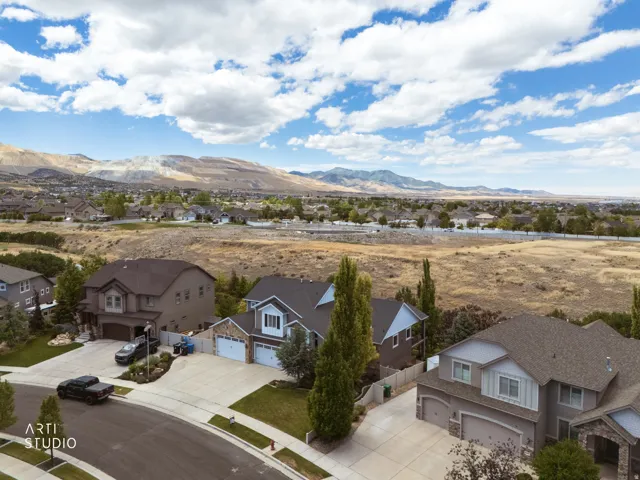 Residential neighborhood featuring homes with multi-car garages and concrete driveways, set against a backdrop of distant mountains and open terrain