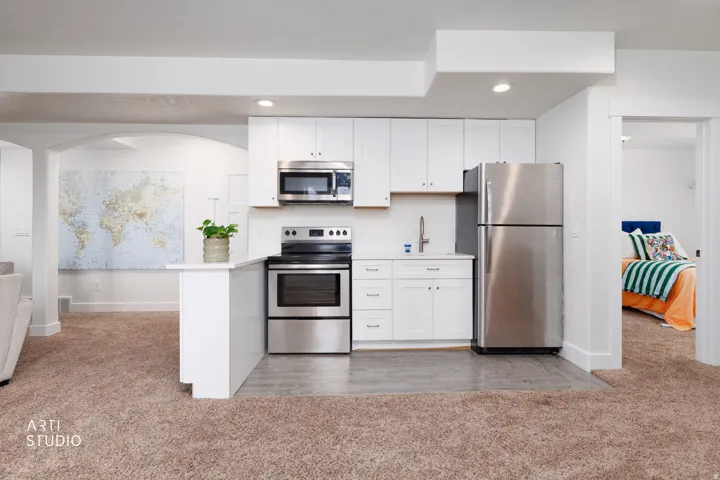 Compact kitchen featuring white cabinetry, stainless steel appliances, a single-basin sink with a gooseneck faucet, and wood-finish flooring