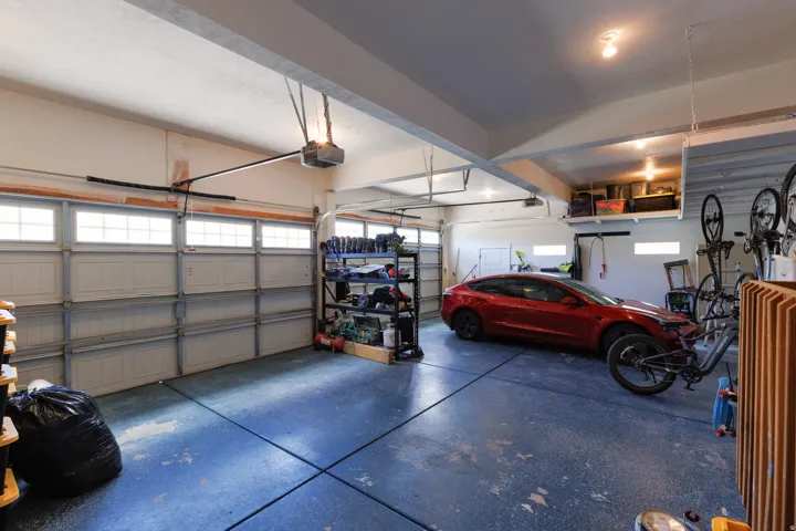 Two-car garage featuring a painted concrete floor and overhead storage shelving