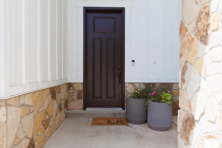 Entryway featuring board and batten siding with a natural stone veneer base