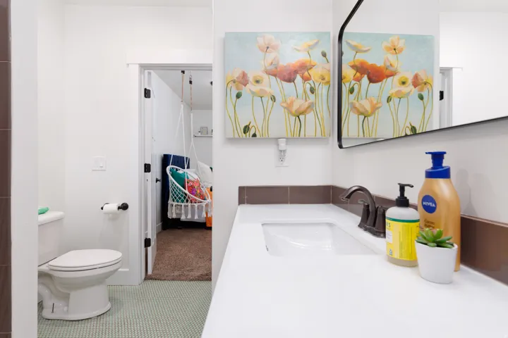 Bathroom featuring a white vanity with integrated sink, dark bronze-finish faucet, and coordinating wall-mounted mirror