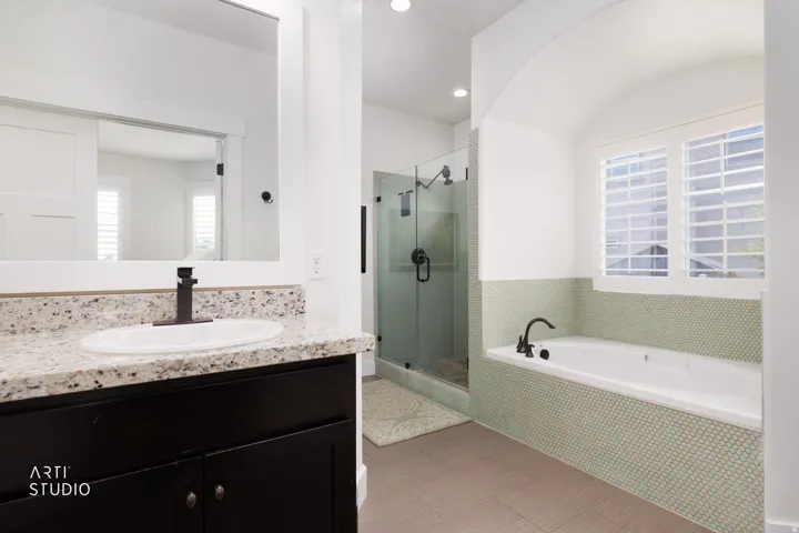 Contemporary bathroom featuring a built-in soaking tub with penny tile surround, glass-enclosed shower, and a vanity with a granite countertop and oval undermount sink