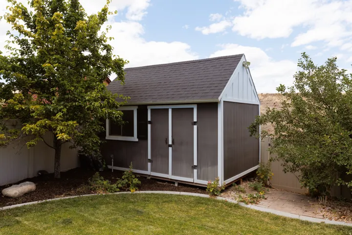 Utility shed with a dark shingle roof, white trim, and a window