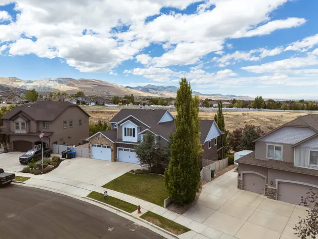 Contemporary two-story residence featuring a gray exterior with white trim, stone accents, and a dark shingle roof