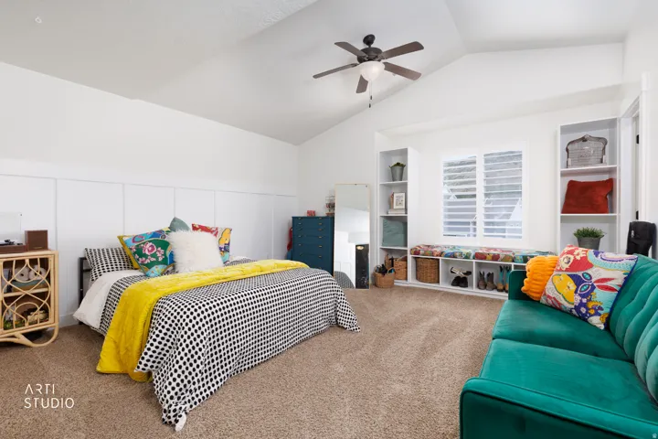 Spacious room featuring vaulted ceilings, a ceiling fan, and carpet flooring