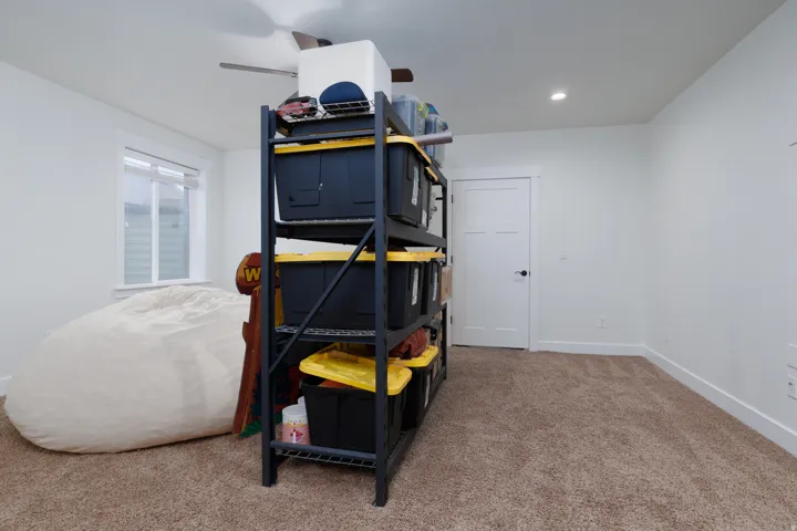 Carpeted room featuring a ceiling fan, recessed lighting, a window with horizontal blinds, and a white paneled door