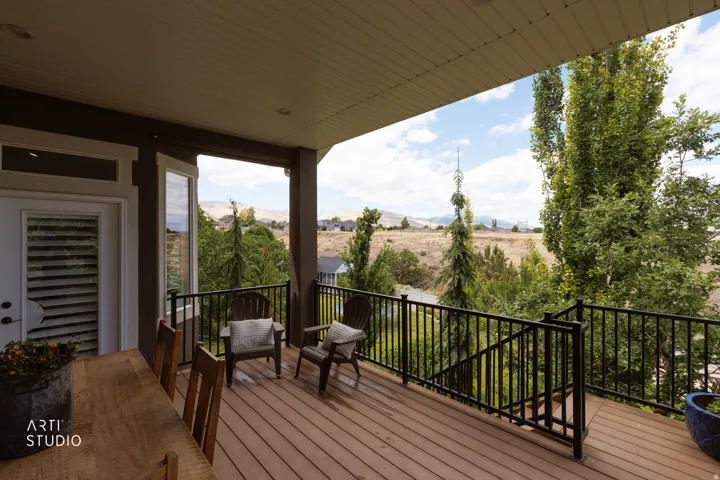 Expansive outdoor deck featuring wood-finish flooring, black metal railings, and a solid overhead covering