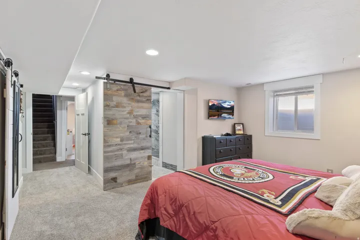Carpeted room with a sliding barn door featuring a wood-finish facade