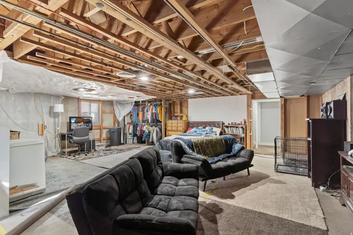 Unfinished basement featuring exposed wood ceiling joists and concrete flooring