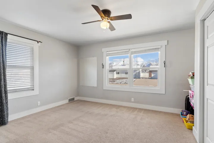 Carpeted room featuring dual windows with blinds, a ceiling fan, and a neutral wall color