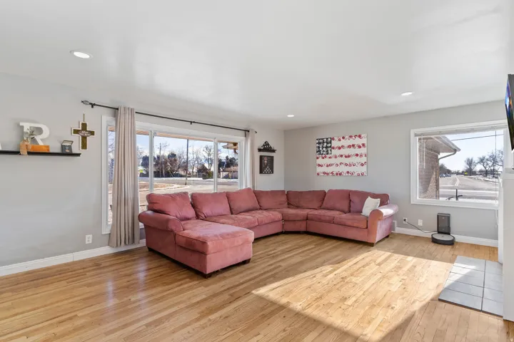 Spacious living area featuring light wood-finish flooring, recessed lighting, and large windows