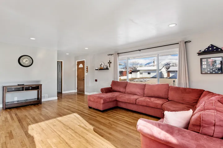 Living area featuring hardwood flooring, recessed lighting, white baseboards, and a large window