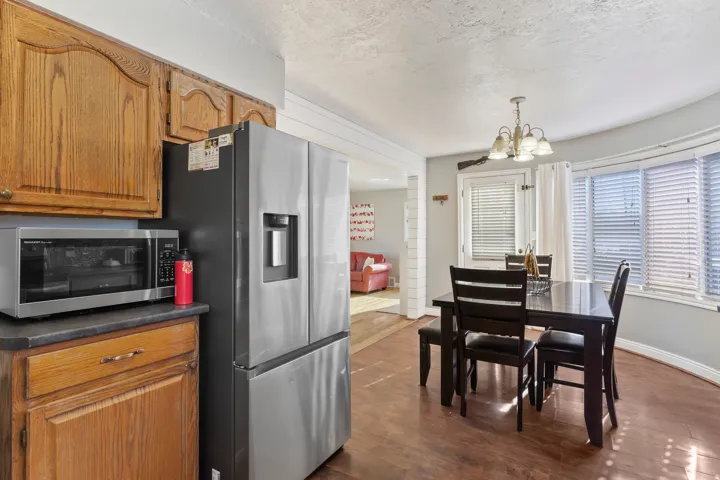 Kitchen and dining area featuring wood-finish flooring, oak cabinetry, and a stainless steel refrigerator